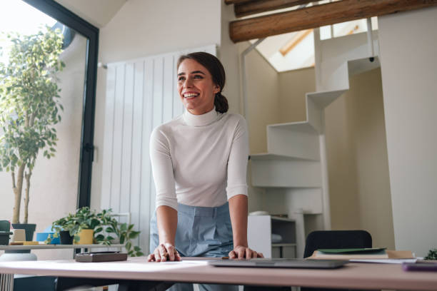 Smiling businesswoman standing in a well-lit modern office environment, exuding confidence and positivity.