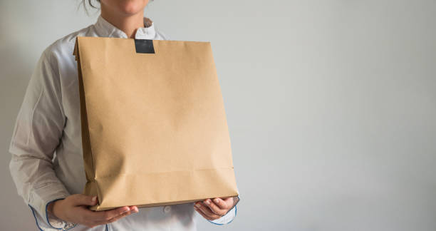 Chef making a delivery of food takeaway in a paper carton bag with copy space