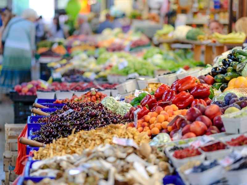 Colorful fresh fruits and vegetables displayed in an open market, illustrating the availability of nutritious foods and the challenge of economic access in the region.