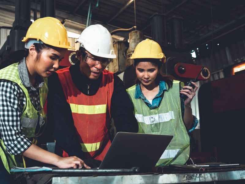 Tech Alignment: factory operators using a laptop to monitor production systems on the shop floor.