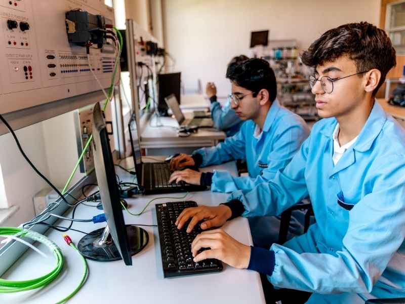 Tech Alignment: engineering training lab with students working on computers and technical equipment.