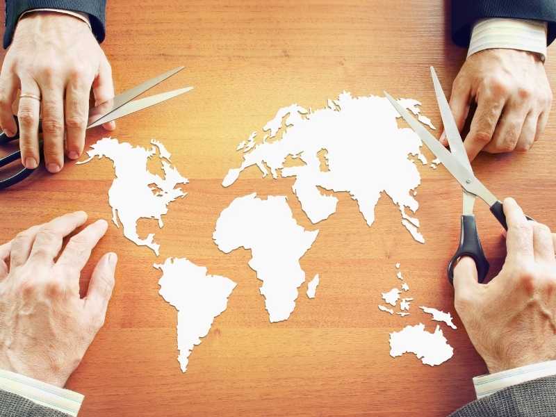 Hands over a world map illustration, representing global factors that influence prices and inflation.