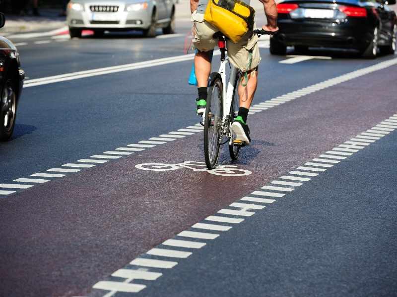 Cyclist riding in a marked bike lane next to cars on a city street.