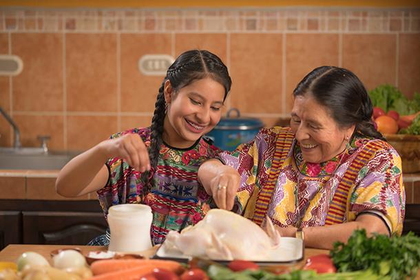 Grandmother and granddaughter preparing a traditional homemade meal together, illustrating how culinary knowledge passes between generations.
